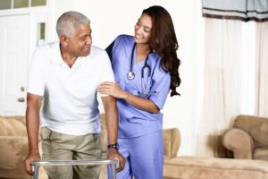 Photo of a Nurse, in blue scrubs assisting a Veteran Use his walker.